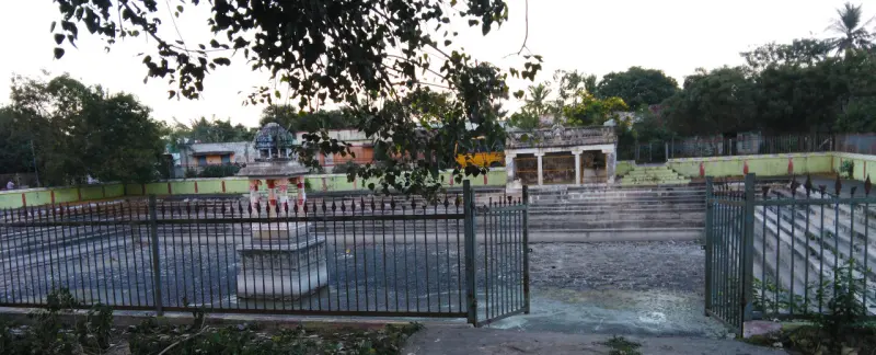 Stepped tank behind an iron railing, with a small pillared mandapam at its centre