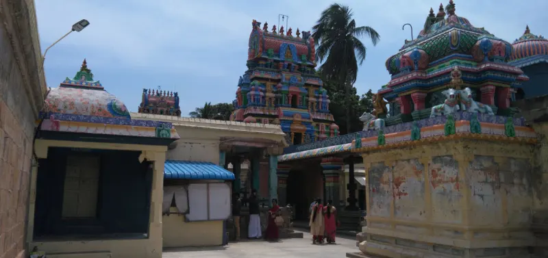 Colourful temple towers and shrine roofs above a courtyard, with devotees walking below