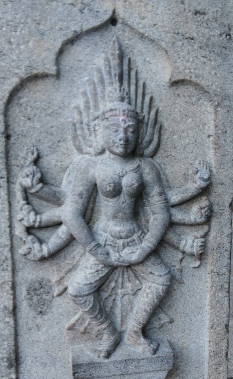 Standing goddess with eight arms and a flame-like crown carved on a pillar