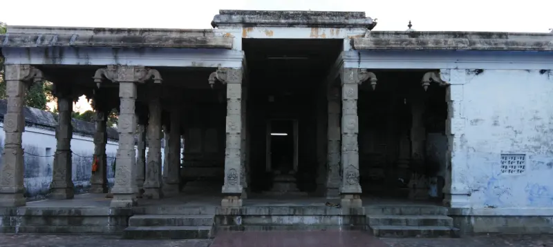 Wide stone hall with rows of pillars and steps, a dark passage in the centre