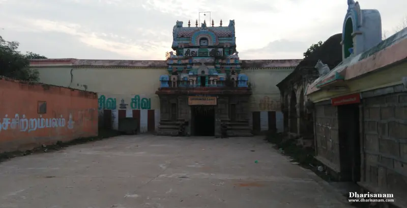A temple tower with a gateway and a wide paved courtyard in front, under a cloudy sky.