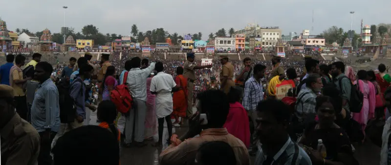 Dense crowd of pilgrims with temple towers behind