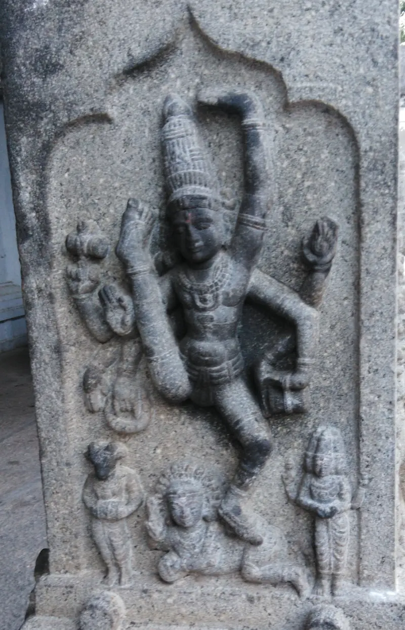 Four-armed dancing figure with a tall crown, with small figures beside it